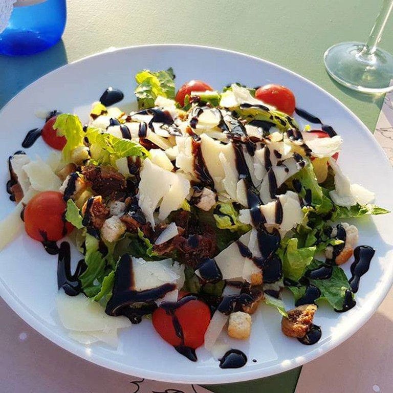 plate with green salad with tomatoes and fish at 'Manalis Winery' restaurant